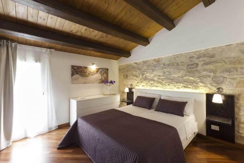 a bedroom with a bed and a stone wall at Casa Hybla in Ragusa