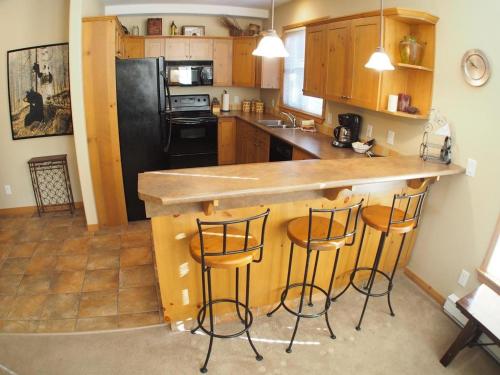 a kitchen with a counter and three stools at a bar at Crystal Forest #60 By Bear Country in Sun Peaks