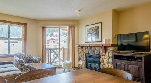 a living room with a television and a fireplace at Fireside Lodge #413 By Bear Country in Sun Peaks