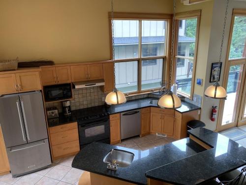 a kitchen with wooden cabinets and stainless steel appliances at On the Run Chalet by Bear Country in Sun Peaks
