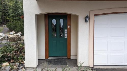 a green door on a house with a garage at Timberline Village #14 By Bear Country in Sun Peaks