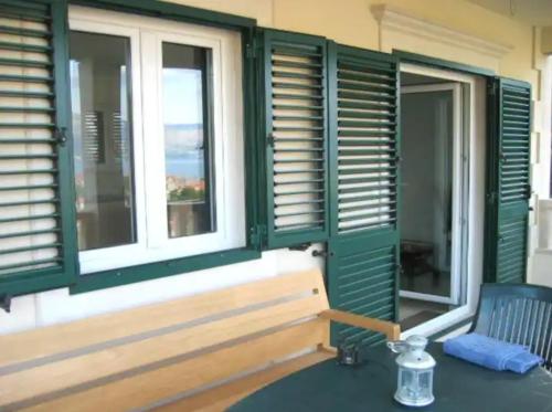 a porch with green shuttered windows and a blue chair at Amazing View Apartment in the heart of Postira in Postira