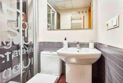 een badkamer met een wastafel, een toilet en een spiegel bij Apartamento moderno Cote in Alicante