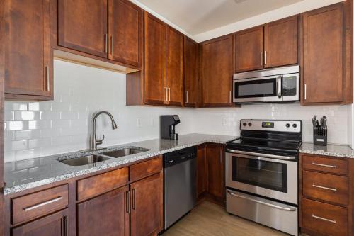 a kitchen with wooden cabinets and stainless steel appliances at Kasa Southside Wilmington in Wilmington