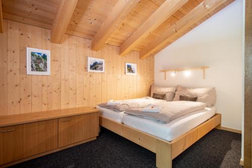 ein Schlafzimmer mit einem Bett in einer Holzwand in der Unterkunft Tälli Hütte in Gadmen