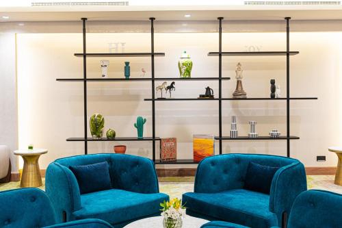 a room with two blue chairs and shelves at Holiday Inn Riyadh The Business District by IHG in Riyadh