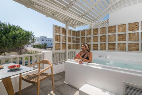 una donna seduta in una vasca da bagno su un balcone di Orama Suites Milos ad Adámas