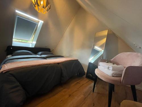 a bedroom with a bed and a chair in a attic at Charmant, ontspannen Molenzicht in Ootmarsum
