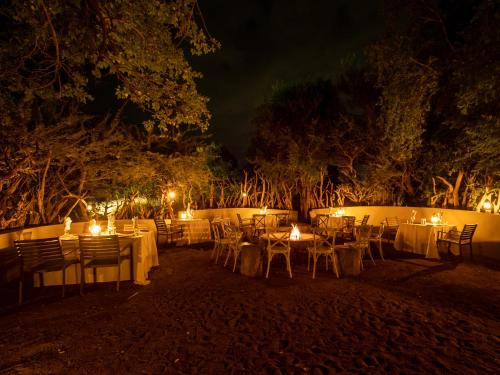 a group of tables and chairs with lights at night at Lush Private Game Lodge in Pilanesberg
