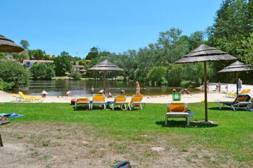 - un groupe de chaises longues et de parasols sur une plage dans l'établissement Village Le Chat 3 Écuras, à Écuras