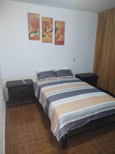 a bedroom with a bed with three paintings on the wall at CasaBlanca in Nazca
