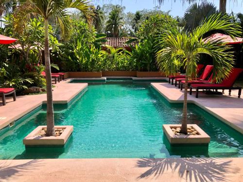 a swimming pool with two palm trees in a resort at Casita Linda, a luxury house near the beach! in Zihuatanejo