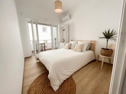 a white bedroom with a large bed and a potted plant at Capitão Ribeiro Surf House in Costa da Caparica