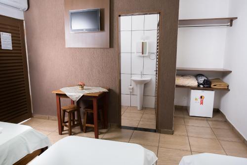een kleine kamer met een tafel en een badkamer bij Hotel Portela III in Olímpia
