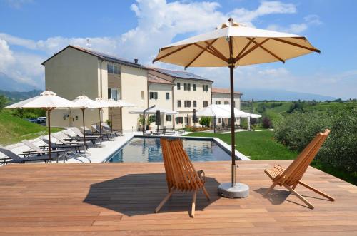 eine Terrasse mit Stühlen, einem Sonnenschirm und einem Pool in der Unterkunft Colonìa Resort in Vittorio Veneto