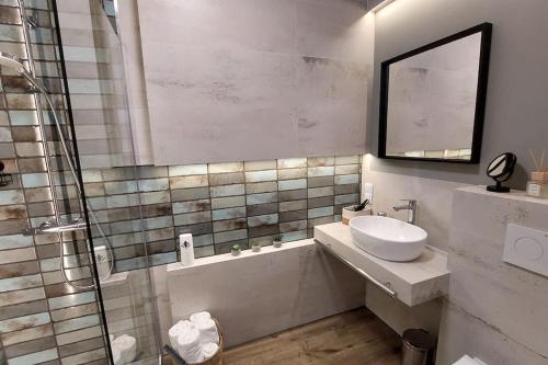 a bathroom with a sink and a shower with a mirror at Wakacyjny apartament & SPA nad morzem in Dziwnów