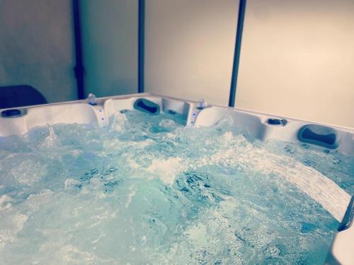 una bañera llena de agua azul en una habitación en Hôtel & SPA Rodier, en Campagnac