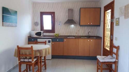 a kitchen with a table and chairs and a microwave at Apartamentos Villa Primera in Cala Figuera