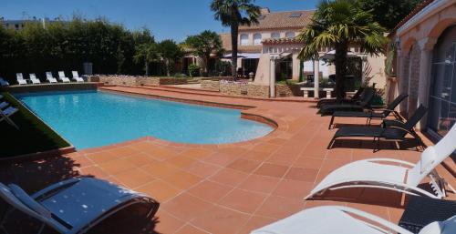 a large swimming pool with chairs and a house at Le Mas Champenois in Chalons en Champagne