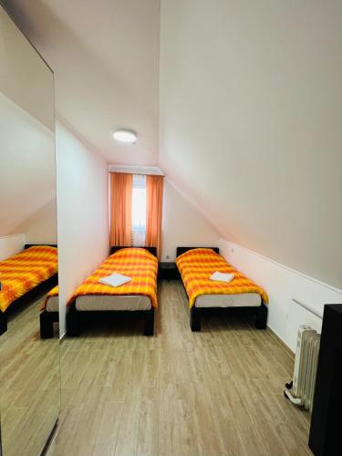 two beds in a small room with orange sheets at Les gites du Valjoly in Touvent
