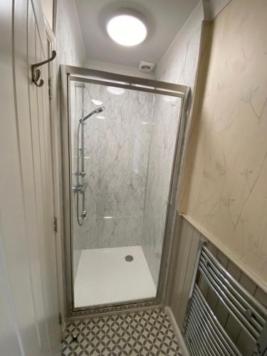 a shower with a glass door in a bathroom at The Lodge at Woodend in Kemnay