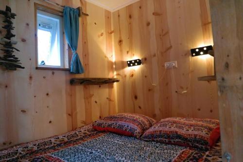 Tiny home Texel في دن بورخ: غرفة نوم بسرير في غرفة بجدران خشبية