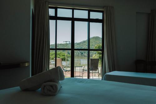 a bedroom with a bed and a large window at Hotel Lago do Sol in Itaúna