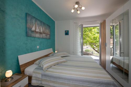 a bedroom with a bed with a blue wall at APARTMAN RUBINIĆ in Ičići