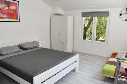a white bedroom with a large bed and a window at Apartmani Katarina in Biograd na Moru