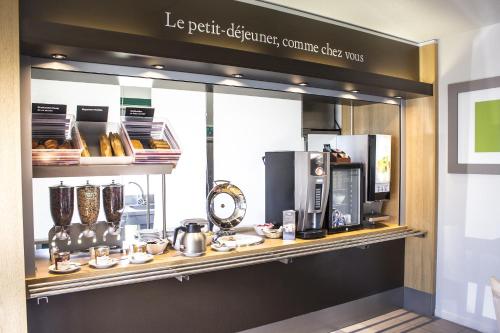 a display case in a coffee shop with a coffee machine at Hotel Inn design Vierzon in Vierzon