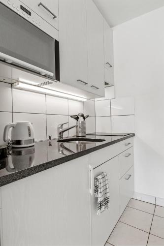 a white kitchen with white cabinets and a sink at Pearlstay - City Center Twin Bed Workplace Washer in Winterthur