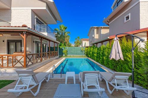 a swimming pool in a house with chairs and an umbrella at Near By THE LAND OF LEGENDS , VİLLA PARADİSE in Belek