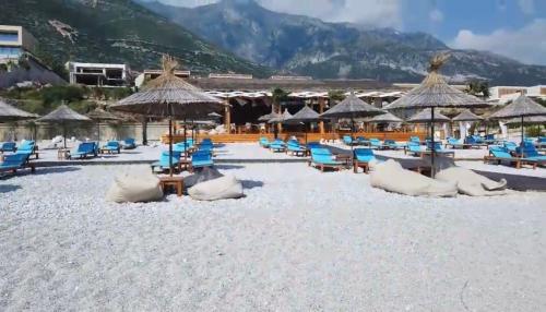 a beach with blue chairs and umbrellas on it at Green Coast Resort V94 in Palasë