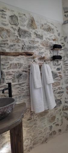 a bathroom with three towels hanging on a stone wall at ClockWise Earthy Vibe House in Apano Chora in Ano Syros