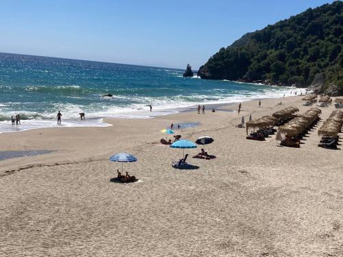 a beach with people sitting under umbrellas on the sand at Serenity Living Pelion in Makrirrákhi