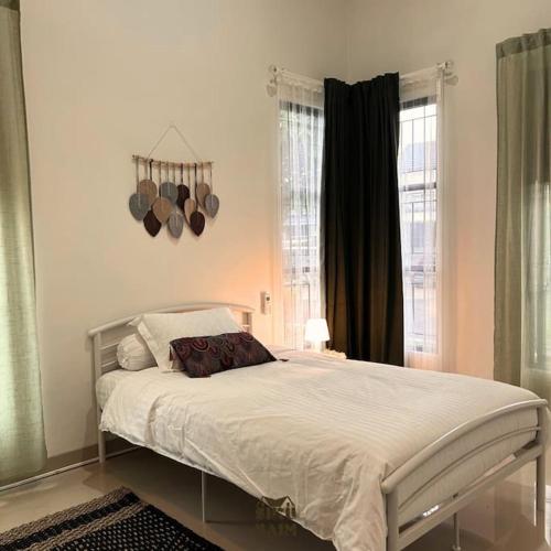 1 dormitorio con 1 cama grande con sábanas blancas en Villa Siku Naim, Sukabumi, en Sukabumi