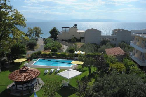 a swimming pool with chairs and umbrellas and the ocean at Iliahtida Apartments in Rovies