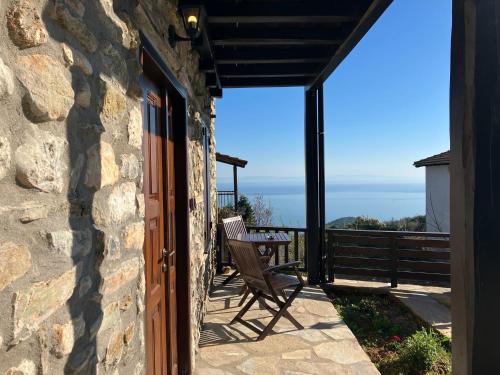 a stone house with a chair on a balcony at Melofegaro Guesthouse in Palaios Panteleimon
