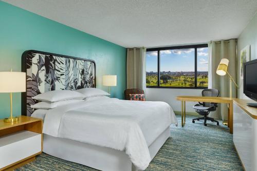 Schlafzimmer mit einem Bett, einem Schreibtisch und einem TV in der Unterkunft Sheraton Miami Airport Hotel and Executive Meeting Center in Miami