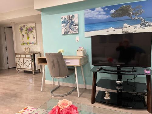 a living room with a large television and a desk at Kelowna little Island near Downtown, lake, hospital and Okanagan Collage in Kelowna
