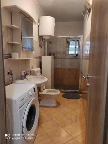 a bathroom with a washing machine and a toilet at Apartman Lucia in Bilice