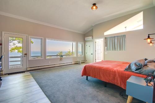 a bedroom with a bed with a red bedspread and windows at Bayfront Home with Deck - 4 Mi to Downtown Plymouth! in Plymouth