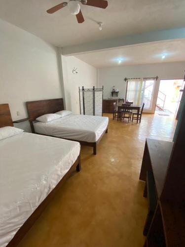 a bedroom with two beds and a dining room with a table at Casa Suites Minizoo in Puerto Escondido