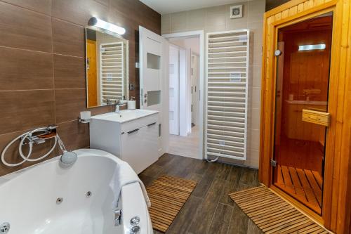 ein Badezimmer mit einer weißen Badewanne und einem Waschbecken in der Unterkunft Ski & Sun B9 in Liptovský Mikuláš