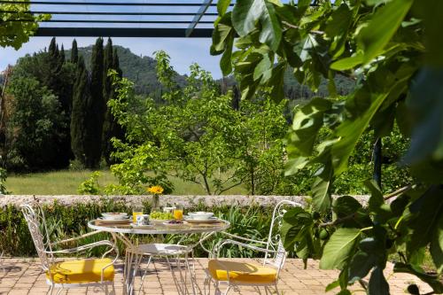 a table and chairs in a garden with trees at Pelecas Country Club in Pelekas