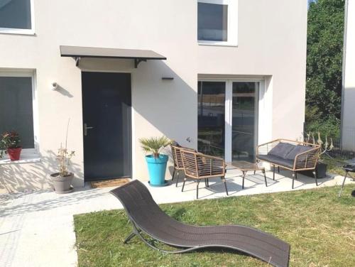 een patio met 2 stoelen en een bank in het gras bij Maison au Pegasus Bridge & Proche Plage in Bénouville