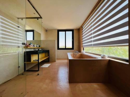 La salle de bains est pourvue d'une baignoire et d'une fenêtre avec des stores. dans l'établissement Maison Luxueuse à Essaouira, à Essaouira