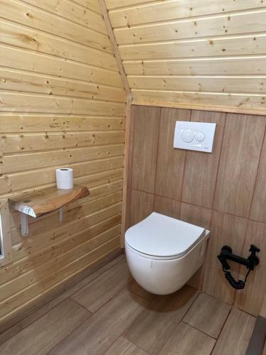 a bathroom with a toilet and a wooden wall at One day in the village/ერთი დღე სოფელში in Batumi