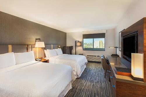a hotel room with two beds and a flat screen tv at Four Points by Sheraton Los Angeles Westside in Los Angeles