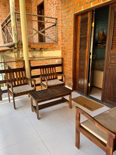 three wooden benches sitting on a porch next to a brick building at Chalé em Barreirinhas in Barreirinhas